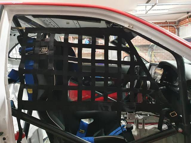 Angled racing window net with four bottom straps attached to roll cage